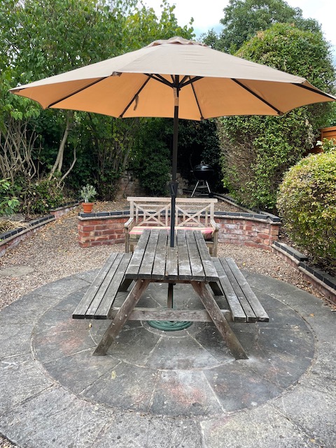 The picnic table in the back garden, with the parasol up